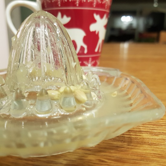 Zitronenpresse mit Saft und weihnachtlicher Tasse im Hintergrund