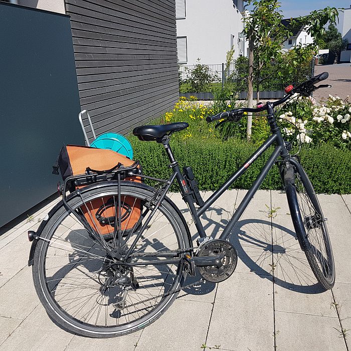 Schwarzes Fahrrad mit orangener Packtasche