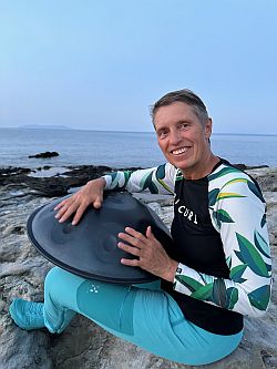 Frau mit Handpan am Strand von Korsika als besonderer Queenager Urlaubsmoment