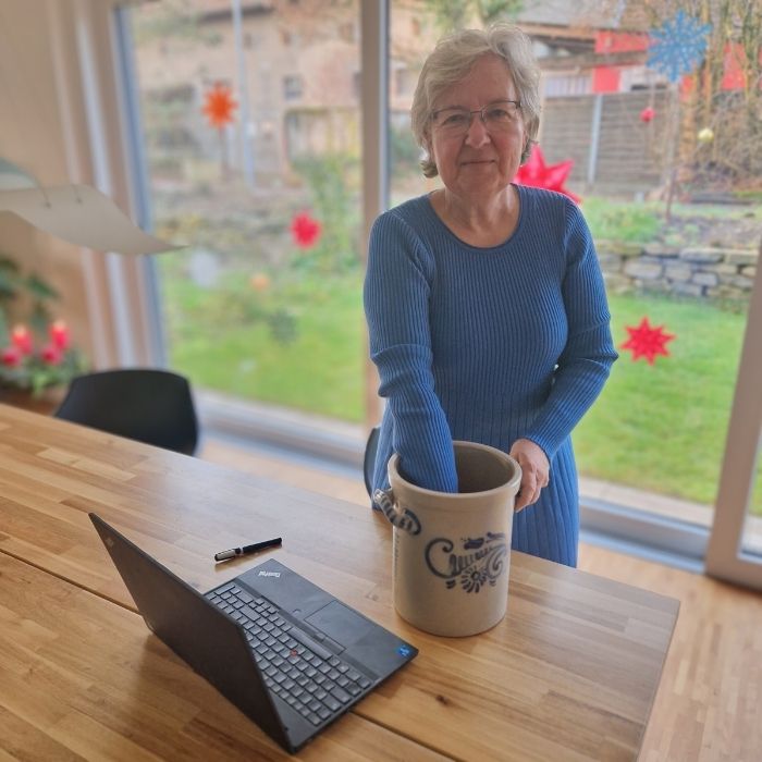 Frau im blauen Kleid greift in einen steinernen Brottopf