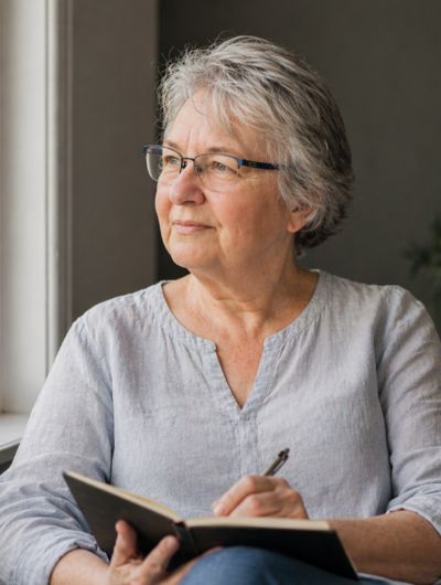 Frau in der Lebensmitte mit Notizbuch – Standortbestimmung mit dem Lebensrad